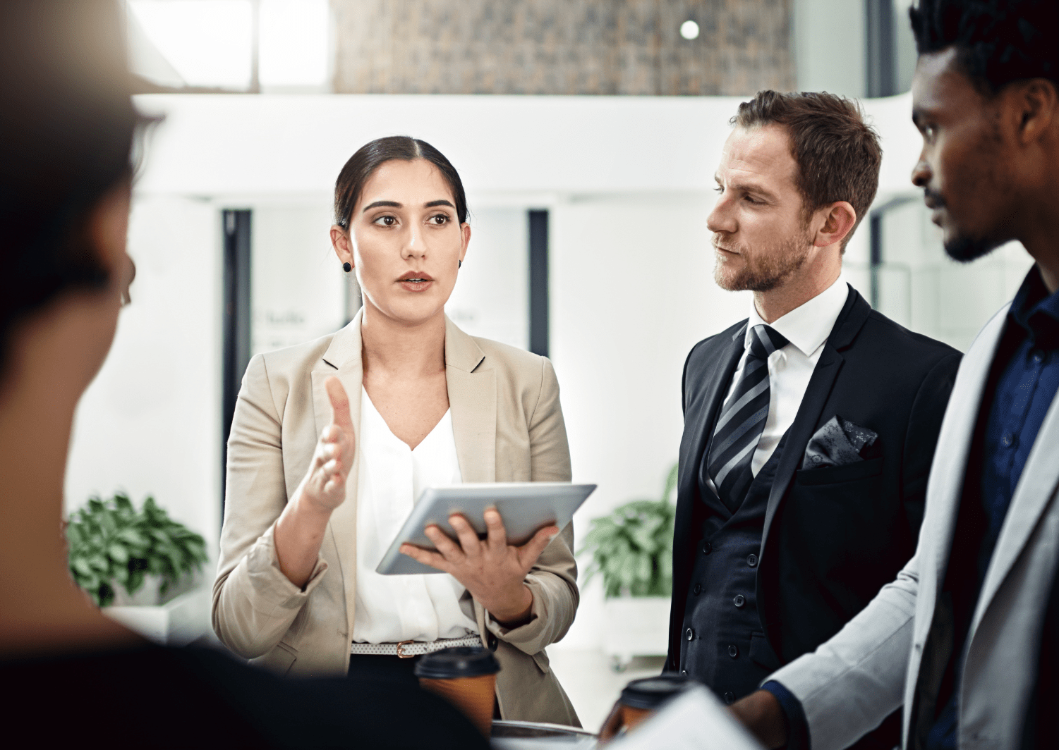 Woman with a tablet in her hand explaining something to three other people.