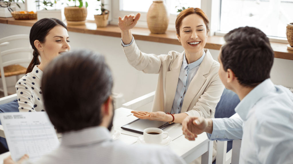 A group of colleagues is engaged in a lively discussion around a table in a bright, modern workspace, highlighting an open and collaborative work environment.
